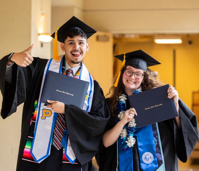 two graduates with diplomas