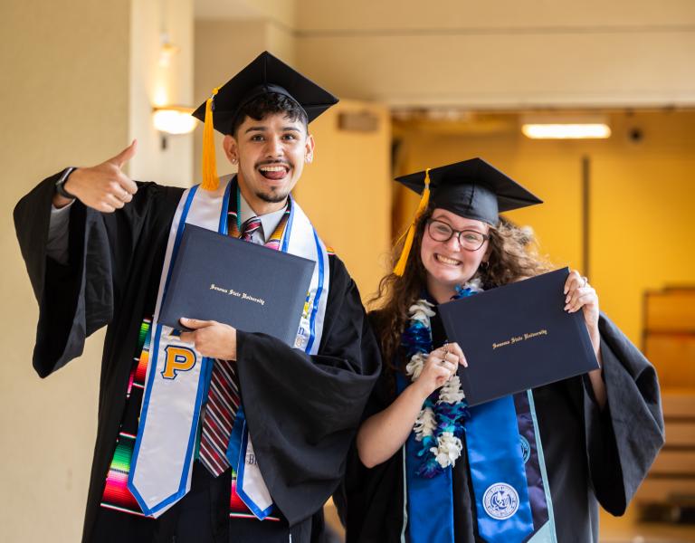 two graduates with diplomas